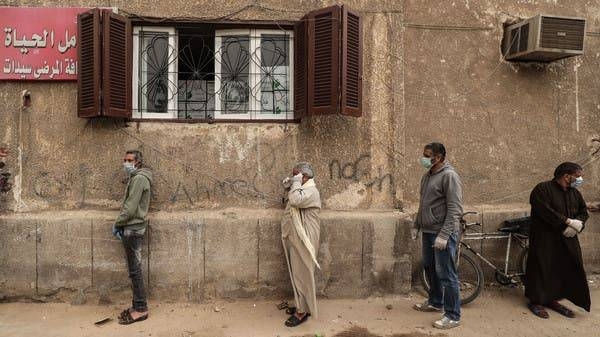 Egyptian men wearing masks wait outside a center of non-governmental organization Egyptian Food Bank to receive cartons with foodstuffs. -- Courtesy photo
