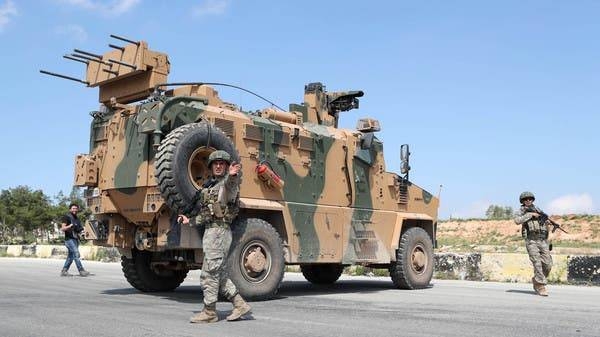Turkish troops stand next to one of their armored vehicles as they secure the road between Saraqeb and Ariha in Syria's opposition-held northwestern Idlib province last week. -- Courtesy photo