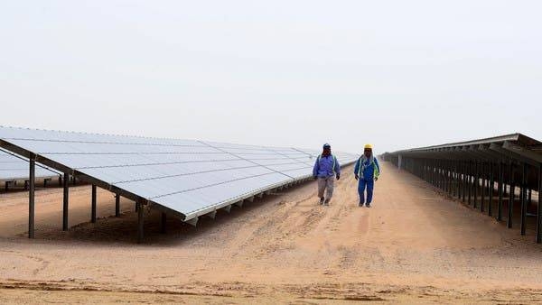 Employees walk past solar panels at the Mohammed Bin Rashid Al-Maktoum Solar Park near Dubai. -- File photo
