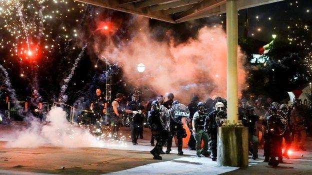A firework explodes near a police line during a protest in Atlanta.
