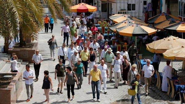 People, most of them wearing masks, walk on a street in Muscat in this file photo.