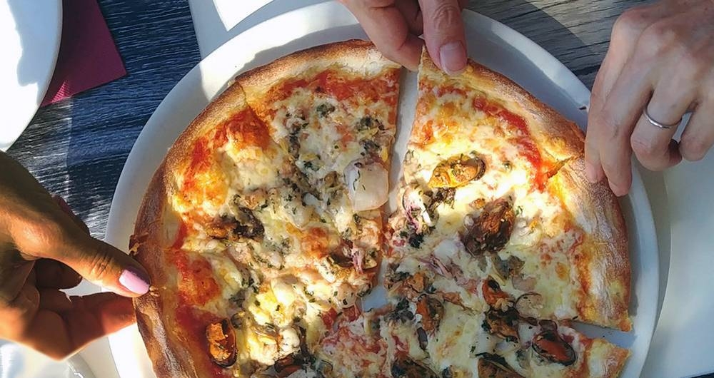 Friends visiting Croatia share a fresh pizza in Makarska, illustrating the importance of food safely to tourism and economic prosperity. — courtesy Eric Ganz