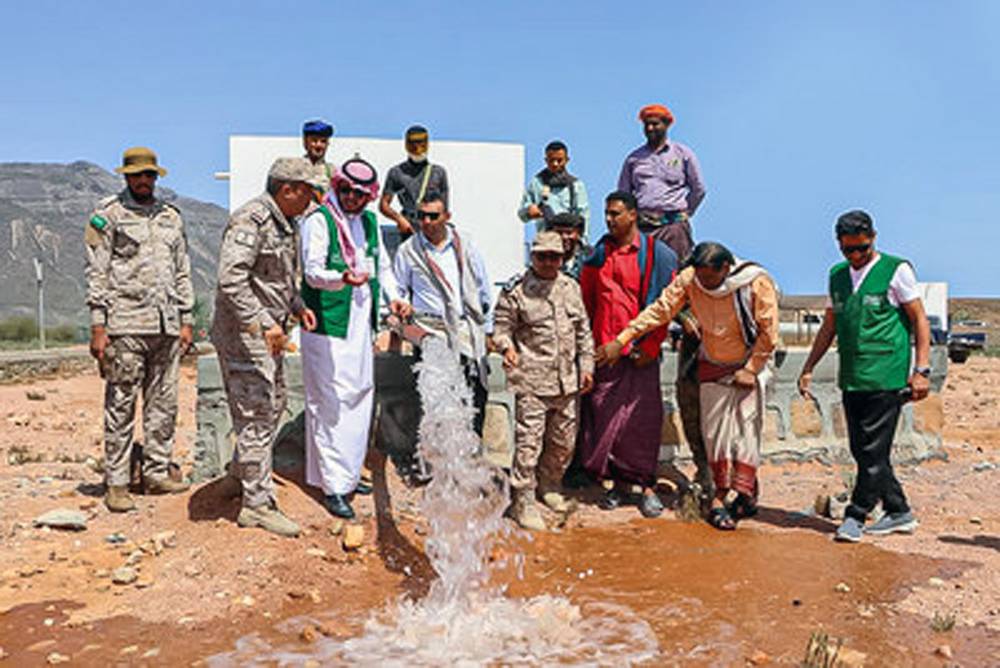 Water flowing in desert with men directing it.