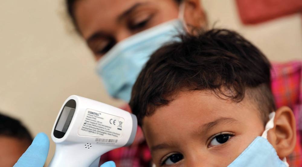 Doctor taking temperature to a family of returnees quarantined in temporary shelter in Venezuela. — courtesy OCHA/Gema Cortes