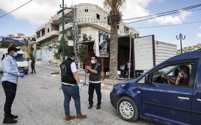 Mask-clad Palestinian security forces stand at a checkpoint in the village of Tafouh, west of Hebron in the West Bank, while enforcing a lockdown due to a surge of new cases of coronavirus. — Courtesy photo