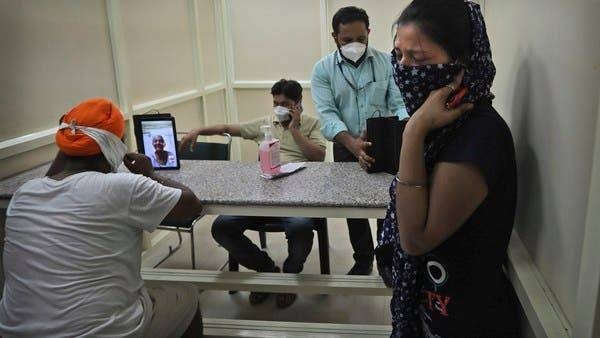 A man speaks with his mother who has been admitted in a hospital through a video phone facility by the COVID help desk, as another leaves crying after talking to her relative, outside a hospital, in New Delhi. — Courtesy photo