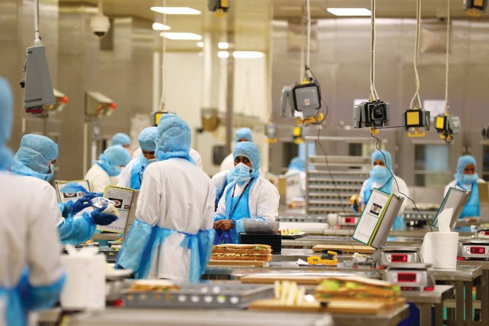 Employees at the catering kitchen of Doha's Hamad International Airport display measures which have been implemented to prevent the spread of coronavirus in this file photo
