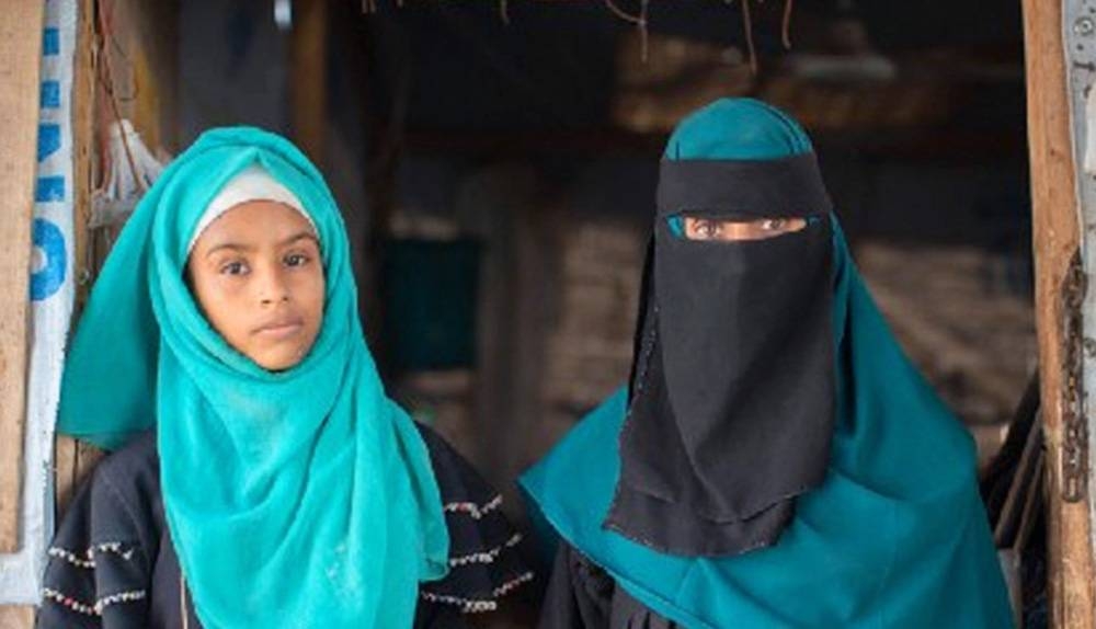 Rania and her eldest daughter, Amani, stand in the entrance to their home in a camp for internally displaced people in Lahj, Yemen. — courtesy WFP/Mohammed Awadh