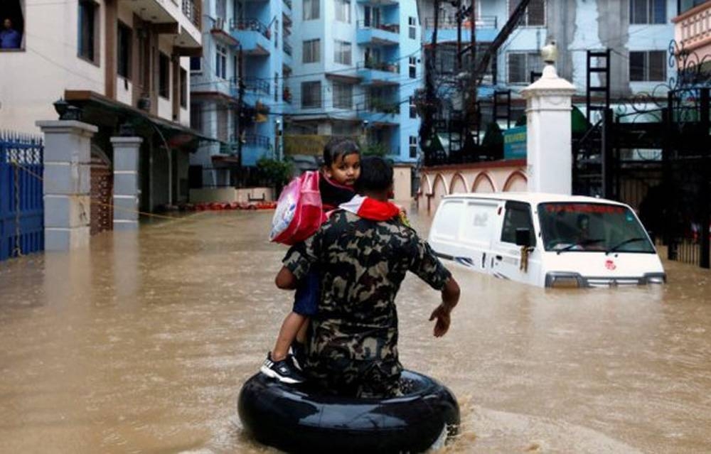 A child is being rescued by the Nepalese security personnel as heavy rains left the streets flooded.