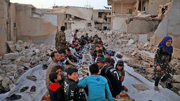 Men and children sit together in the midst of ruins to eat in Aleppo, Syria. — File photo
