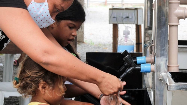 A woman and children use new handwashing facilities installed by UNICEF in Embratel, an informal urban settlement in Boa Vista, in northern Brazil. — courtesy UNICEF/Yareidy Perdomo