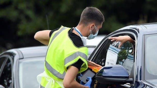 An official delivers a testing kit through a car window at a mobile drive through coronavirus testing center, in Richmond, London. — Courtesy photo
