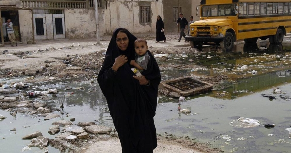 File photo shows woman carrying a toddler crosses a street in the southern Iraqi city of Basra. — courtesy UNICEF/Noorani
