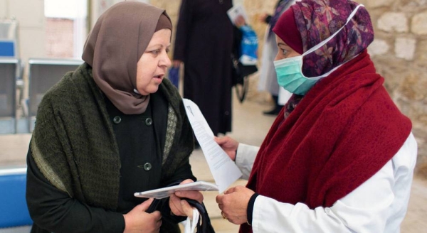A health worker provides COVID-19 information to a patient visiting the Jerusalem Health Center. — courtesy UNRWA/Louise Wateridge