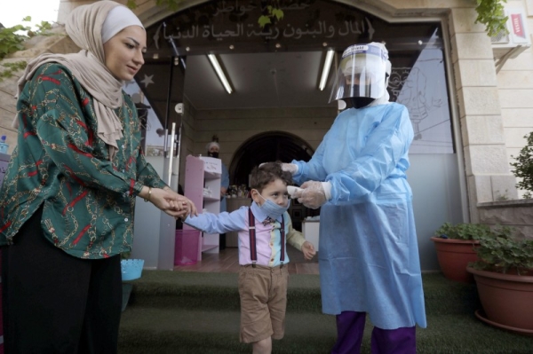 A teacher wearing a protective suit checks the temperature of a child at a nursery after the government eased the coronavirus disease (COVID-19) restrictions in Amman. — Courtesy photo
