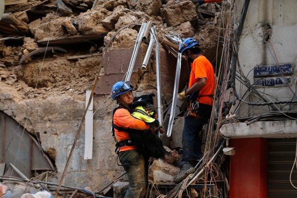 A Chilean rescuer holds a rescue dog as they search in the rubble of a building that collapsed in Beirut port blast, after getting signals there may be a survivor under the rubble. — Courtesy photo