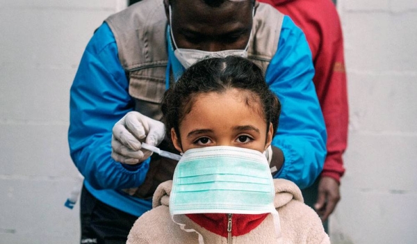 A seven-year-old girl is given a protective mask prior to a health screening in the informal settlement in Rome, Italy, where she lives. — courtesy UNICEF/Alessio Romenzi.