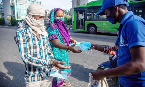 A volunteer distributes free masks to Indians in New Delhi. As part of fundamental and lasting changes in social behavior being ushered in by the coronavirus, COVID-19, pandemic, 107 cities in India are to have pop-up cycle lanes, traffic-calmed sections and non-motorized zones.