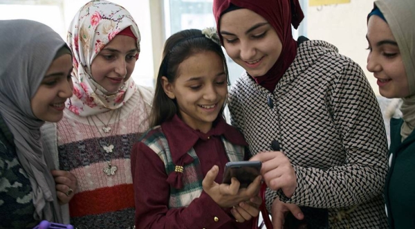 Syrian adolescent girls use a smartphone outside a technology lab in Damietta Governorate, Egypt. — courtesy UNICEF/Shehzad Noorani