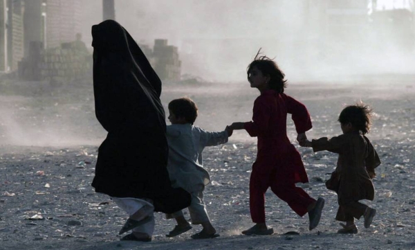 A family runs across a dusty street in Herat, Afghanistan. — courtesy UNAMA/Fraidoon Poya
