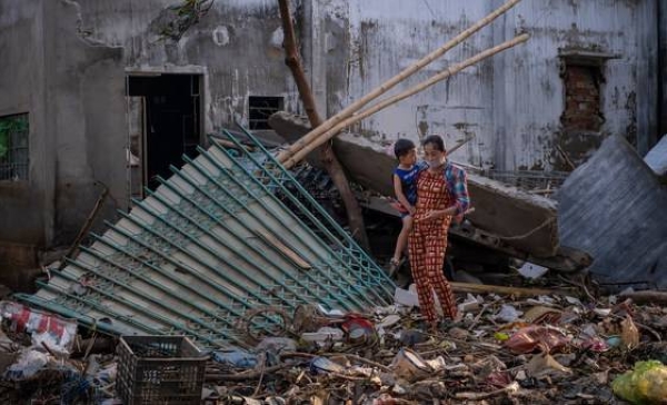 A woman carries her child as she walks past the ruins of a house destroyed by recent floods central Vietnam. — Courtesy photo