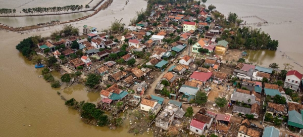 A woman carries her child as she walks past the ruins of a house destroyed by recent floods central Vietnam. — Courtesy photo