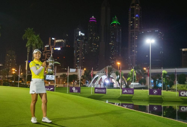 Minjee Lee poses against Dubai skyline with the trophy.