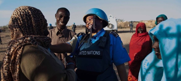 A UNAMID police officer interacts with women at a water point in Nifasha camp for internally displaced persons, north Darfur, in this file picture. — Courtesy photo