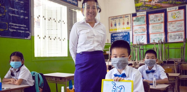 

A teacher and her students practice COVID-19 school re-opening guidelines by wearing face masks and maintaining physical distance at a primary school in Phnom Penh, Cambodia. — courtesy UNICEF/Seng