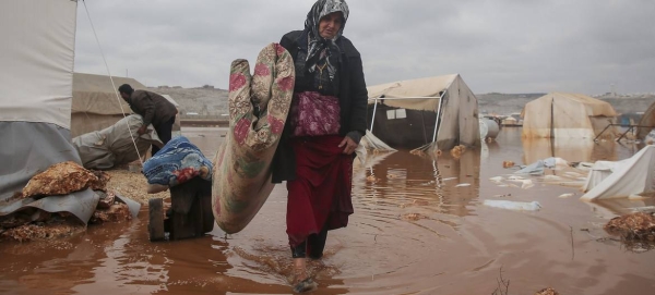 A woman tries to rescue her belongings after floods inundated her camp in northwest Syria. — Courtesy photo