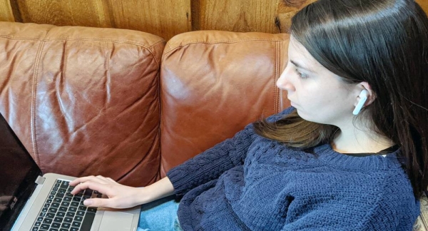 Young woman wears earbuds while working on her laptop. — courtesy UN News/Elizabeth Scaffidi