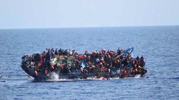 Migrants are seen on a capsizing boat before a rescue operation by Italian navy ships 