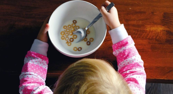 

A little girl eats breakfast while sitting at a table. — courtesy Unsplash/ Providence Doucet