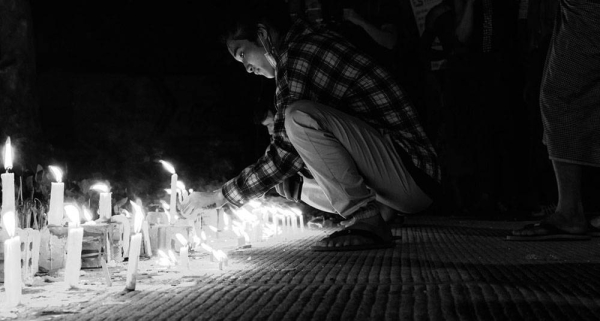 Young man lights a candle during a night vigil in Yangon, Myanmar. — courtesy Unsplash/Zinko Hein