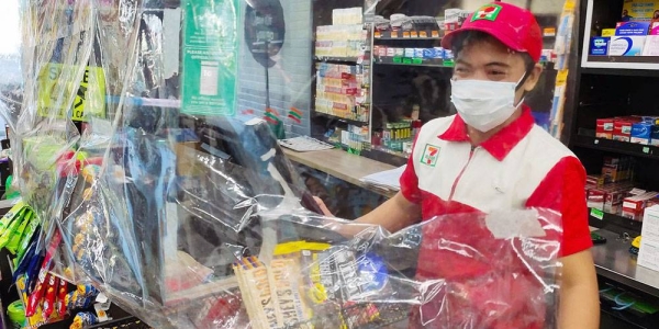 A convenience store requires staff to wear a mask, observe physical distance, and use a plastic sheet barrier as safety measures to prevent the spread of COVID-19, Muntinlupa City, Philippines. — courtesy ILO/Minette Rimando