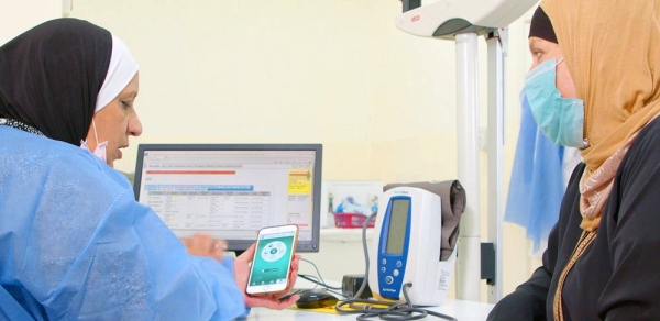 A nurse shows a Palestinian refugee in Jordan a health app on her smart phone. — courtesy UNRWA/George Awwad