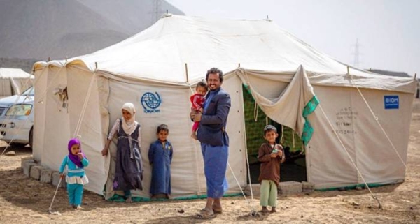 File photo shows a father standing with his children outside their tent in a displacement site outside Marib City, Yemen. — courtesy IOM/Olivia Headon