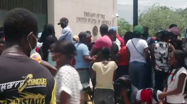 A crowd collects before the US mission in Port au Prince, the capital of Haiti, with the interim government asking the US to deploy troops to protect key infrastructure.