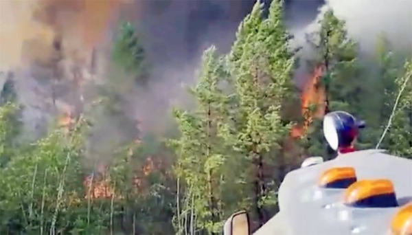 Volunteers and firefighters battle to control the wildfire in the clearing of a Siberian forest.