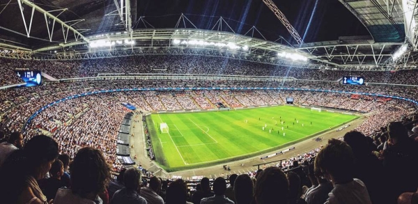 A crowd watching a football game inside Wembley Stadium in England. (September 2016) — courtesy Unsplash/Mitch Rosen