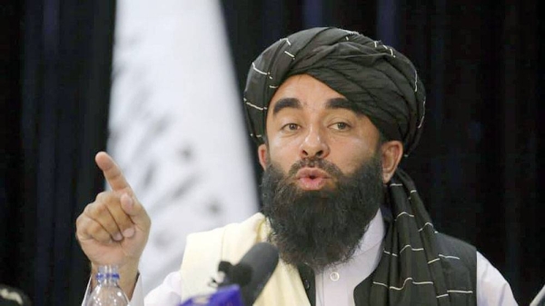 In front of a Taliban flag, Taliban spokesman Zabihullah Mujahid speaks at at his first news conference, in Kabul, Afghanistan, Tuesday.