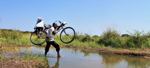 A health worker crosses a stream with his bike on his way to vaccinate children in Tanganyika Province in the Democratic Republic of the Congo. — courtesy UNICEF/Serge Wingi