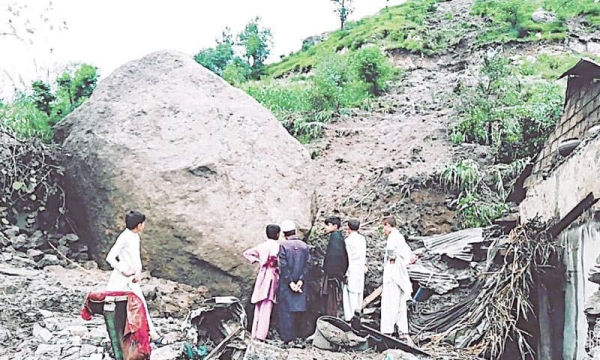 People on Wednesday stand next to a boulder after it hit a house in Manshera. — courtesy Dawn