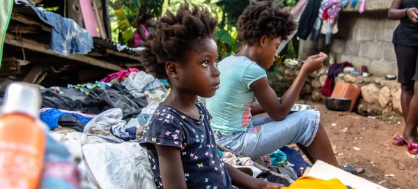 Children sit in the rubble of the house they lost in an earthquake in Haiti.