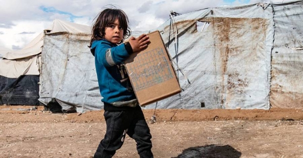 A child carries winter clothing kits, distributed by UNICEF, in Al-Hol camp in northeastern Syria. — courtesy UNICEF/Delil Souleiman