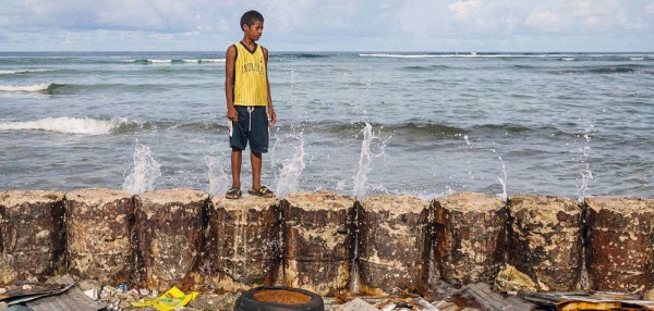 A boy stands on a seawall that protects his family home from the rising seas in Majuro Atoll in the Marshall Islands. — courtesy UNICEF/Vlad Sokhin