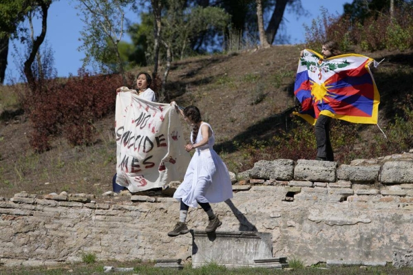 Protesters hold a Tibetan flag and a banner during the Olympic flame lighting ceremony for the Beijing 2022 Winter Olympics.