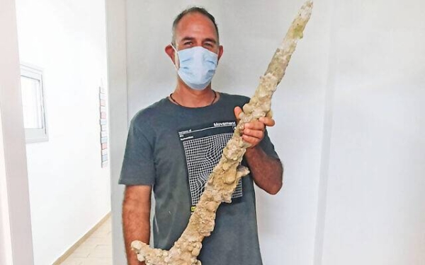 A picture released by Israel Antiquities Authority shows diver Shlomi Katzin with the sword he found.