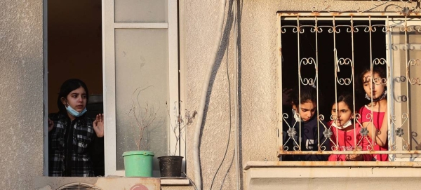 Palestinian children look out from their house window at destroyed buildings in their neighborhood in the Gaza City.