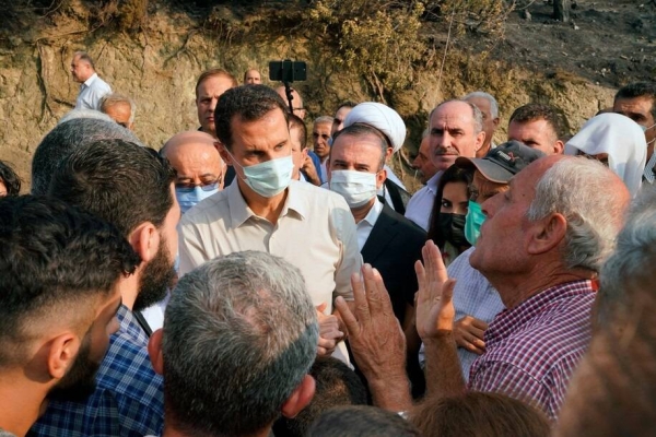 President Bashar Al-Assad speaks with people during his tour of areas that suffered heavy damage from deadly wildfires, in the Syrian coastal province of Latakia.